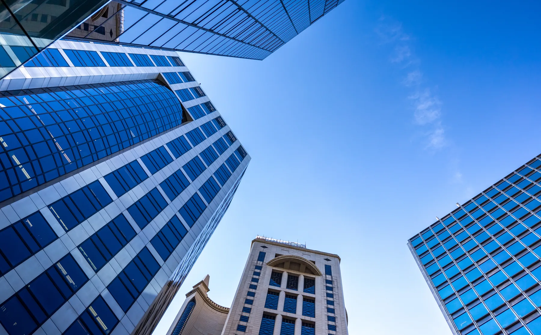 Blue glass towers under a clear sky, looking up