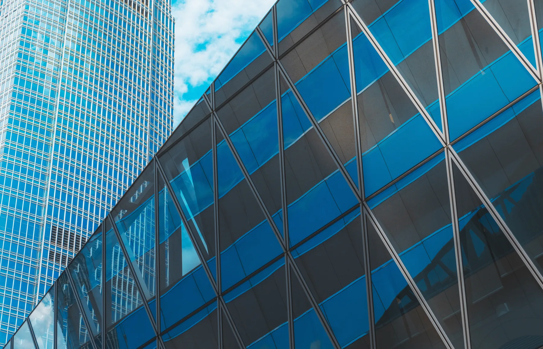 A diagonal glass grid facade, looking up