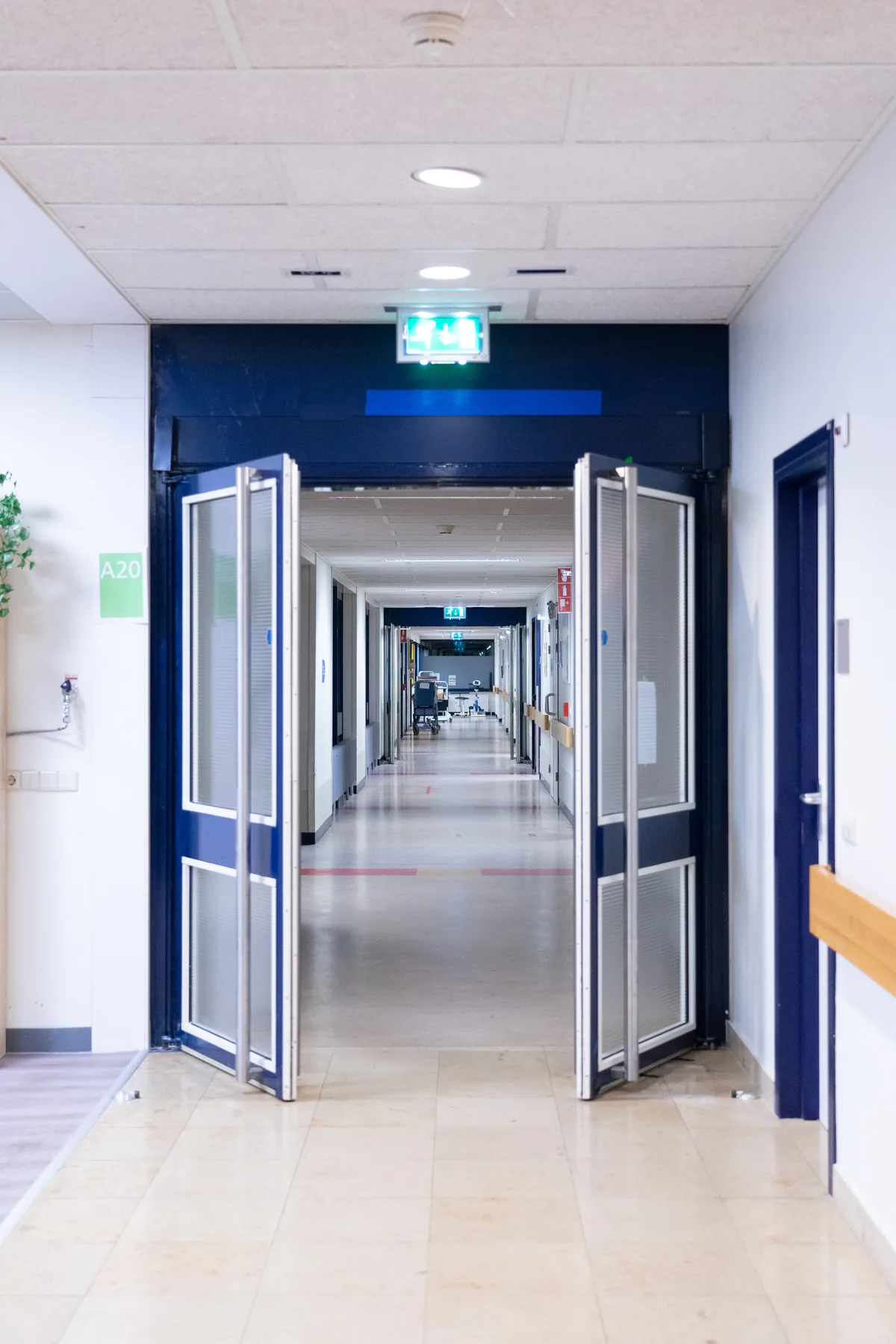 A hospital corridor through open blue doors