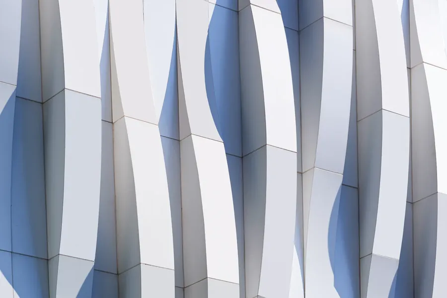 White sculpted fins on a building, looking up into a blue sky