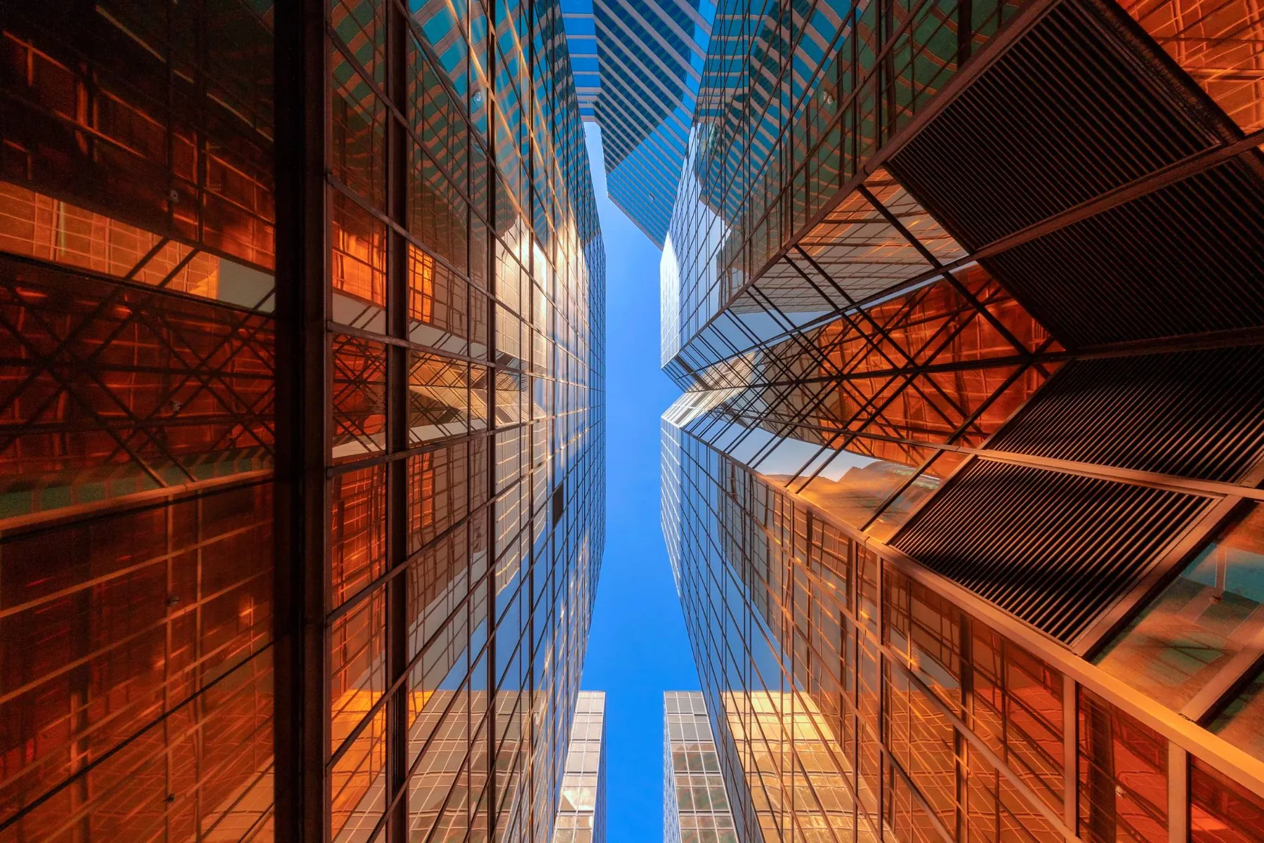 Gold glass towers looking straight up to a slit of blue sky