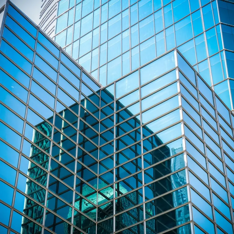 Blue glass office blocks with a teal tower reflected
