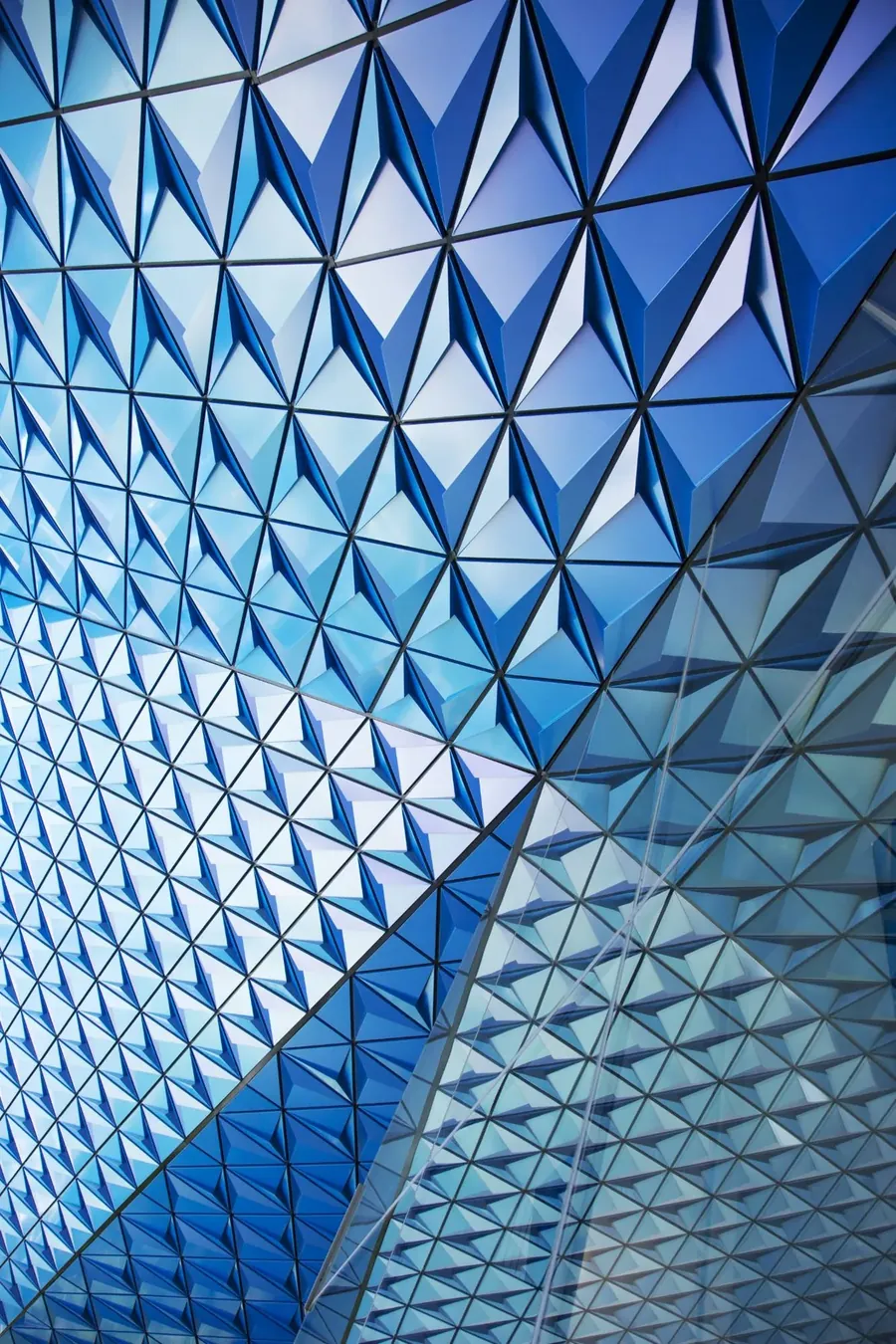 Blue triangular facade panels behind a sheet of glass