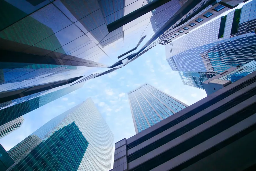Glass towers looking straight up to a cloud-flecked sky