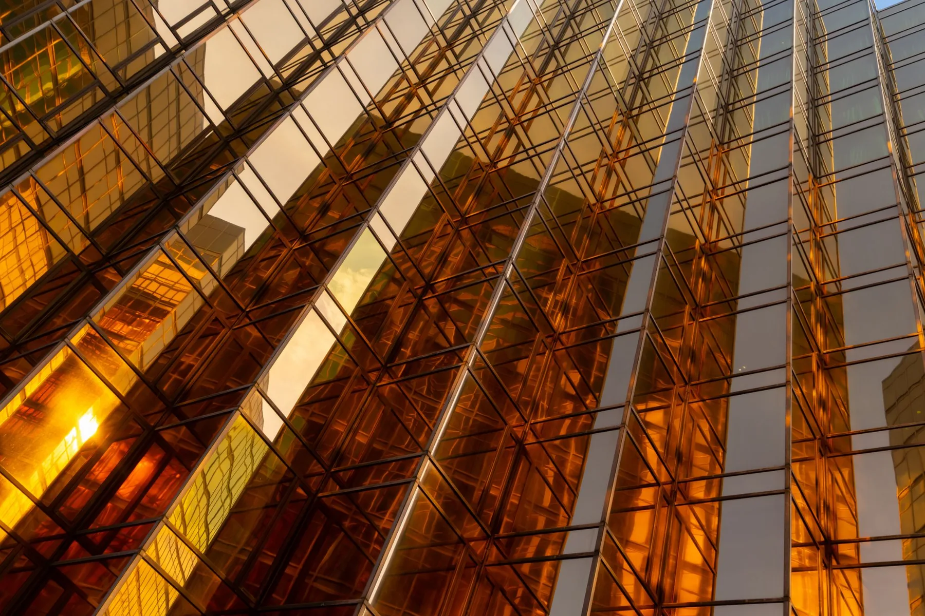 Gold mirrored facade rising diagonally with a sun flare