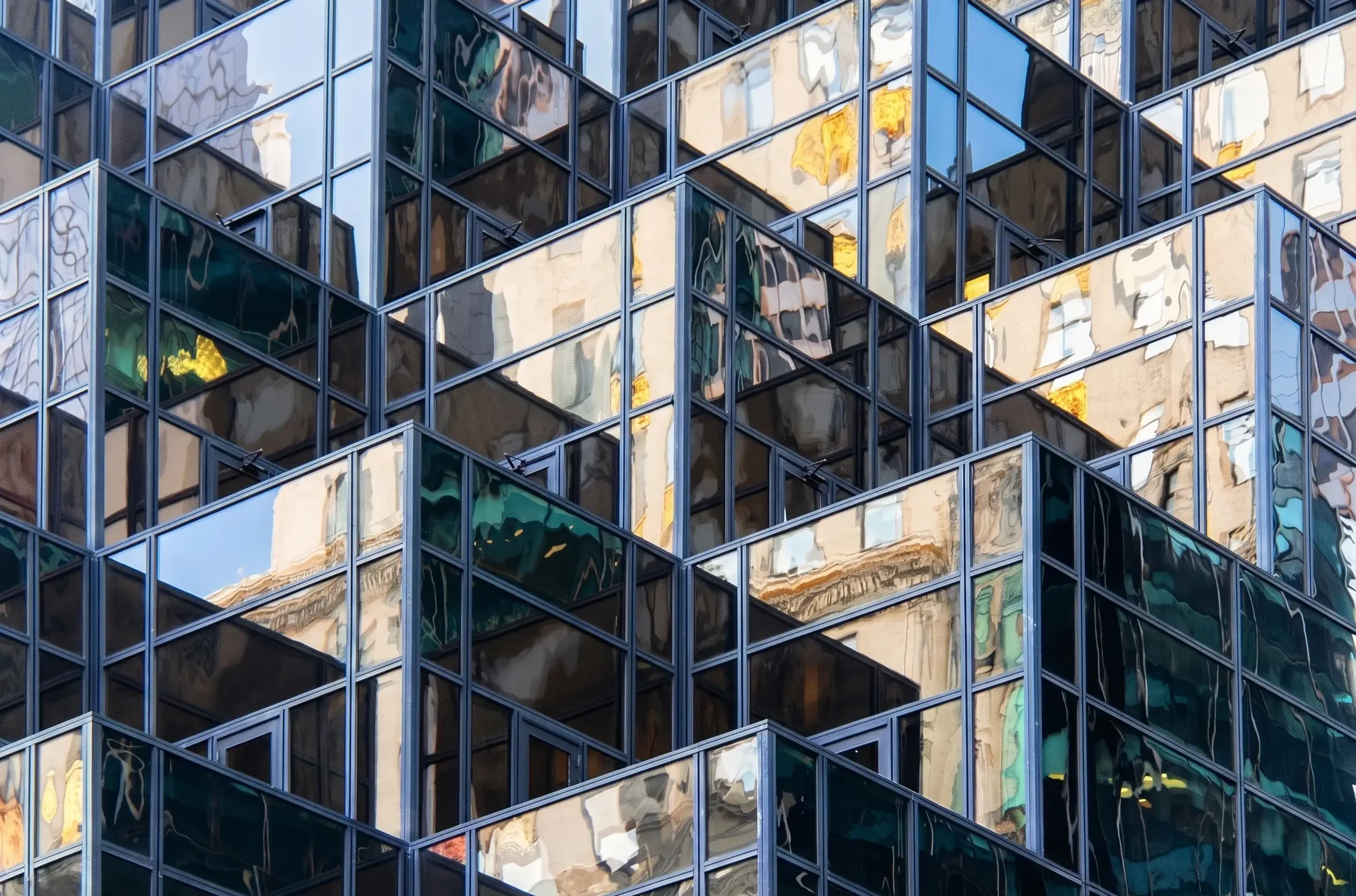 A stepped glass tower reflecting the stone buildings around it