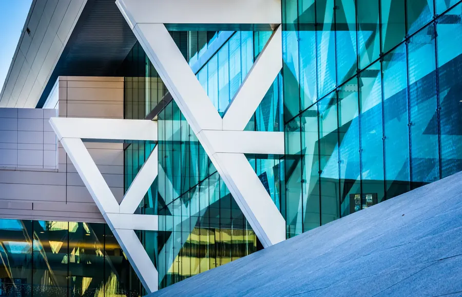 White structural trusses against a facade of blue glass