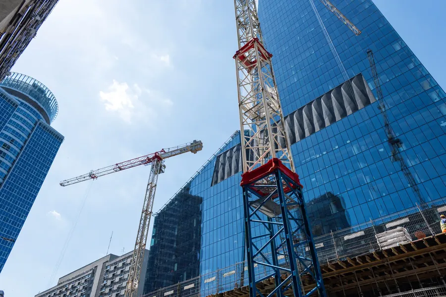 Tower cranes beside a blue glass tower