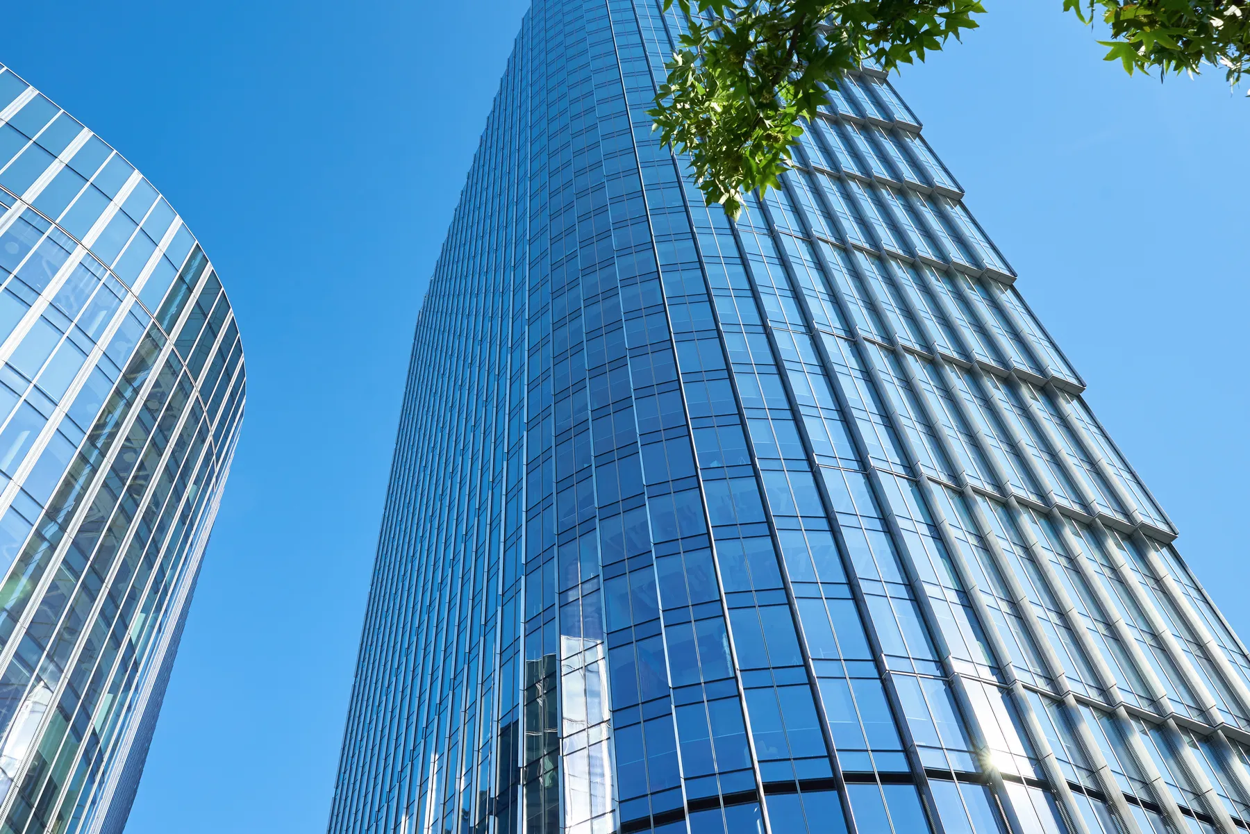 A curved blue glass tower, looking up